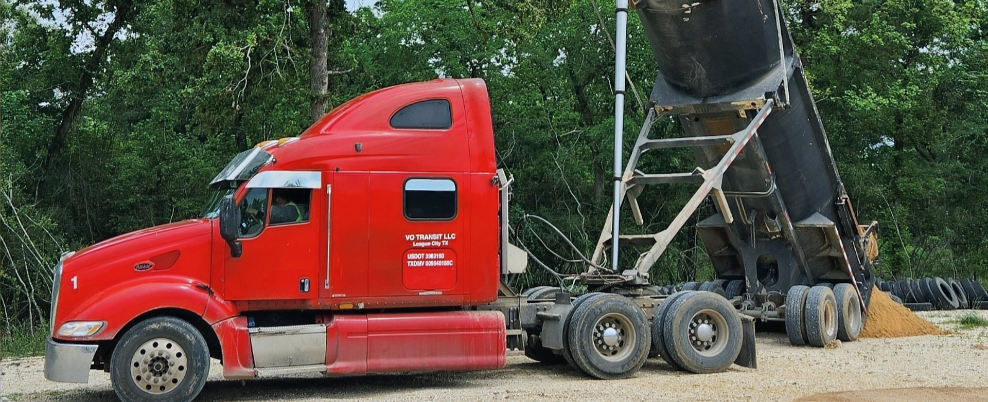 Red dump truck unloading sand